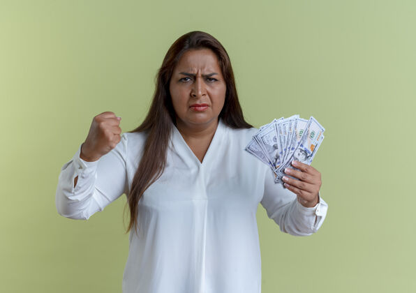 严格严格随意的白人中年女子手持现金举起拳头孤立在橄榄绿的墙上橄榄提高现金