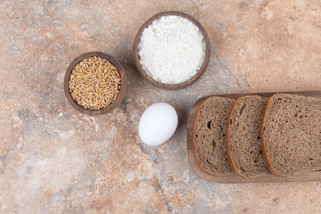 切片黑面包片 面粉 大麦和鸡蛋放在大理石表面大麦谷类碗