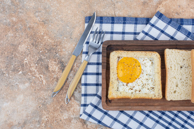 鸡蛋木盘上放有香料的鸡蛋吐司和餐具面包草药桌布