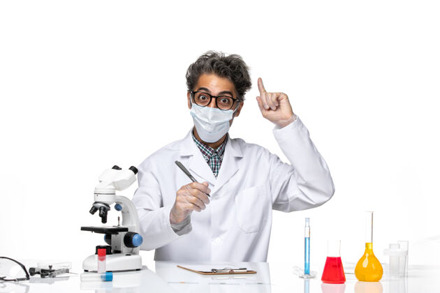 坐正面图身着特殊套装的中年科学家坐着写笔记前面实验化学