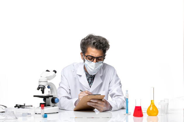 成人正面图中年科学家穿着特别套装坐着写笔记科学人实验室外套
