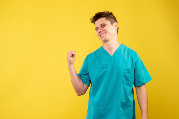 成人正面图黄色背景上穿着医疗服的年轻男医生男性男人站立
