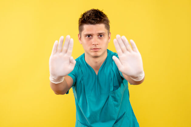 健康正面图年轻的男医生穿着医疗服 戴着黄色背景的手套男人背景手套