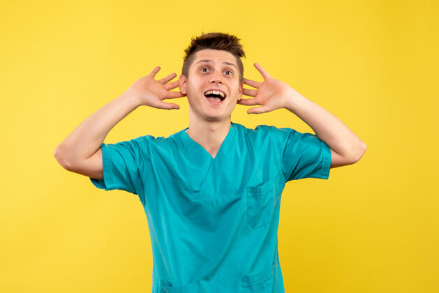 背景正面图黄色背景上穿着医疗服的年轻男医生肖像医学休闲