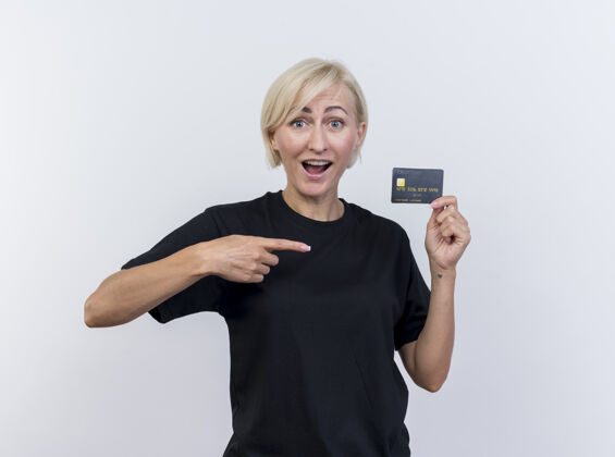 金发令人印象深刻的中年金发斯拉夫妇女出示信用卡指着它看着隔离在白色背景上的相机信用指向印象