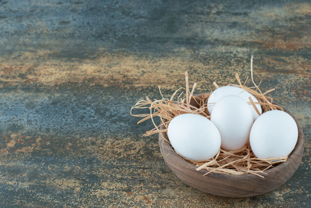 生的新鲜的鸡蛋躺在干草木碗上蛋白质稻草生的