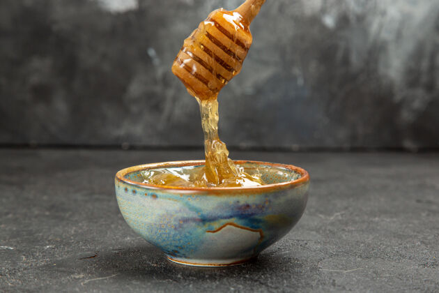正面正面图甜甜的蜂蜜在黑暗的盘面上甜甜的蜂蜜甜甜的蜜蜂餐具蜂蜜甜味剂