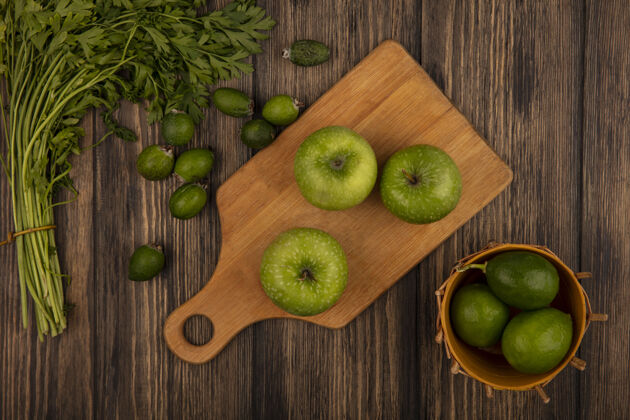欧芹新鲜的绿色苹果放在木制的厨房板上 柠檬放在木桶上 樱桃和欧芹被隔离在木墙上菲乔中心特写