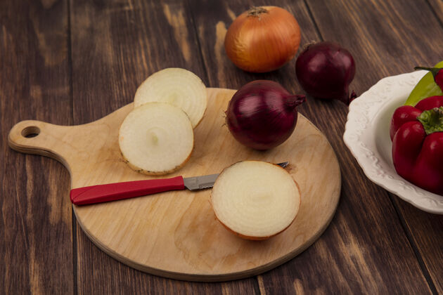 特写顶视图新鲜的洋葱在一个木制的厨房板上用刀与辣椒在一个木制的墙上碗洋葱风景烹饪