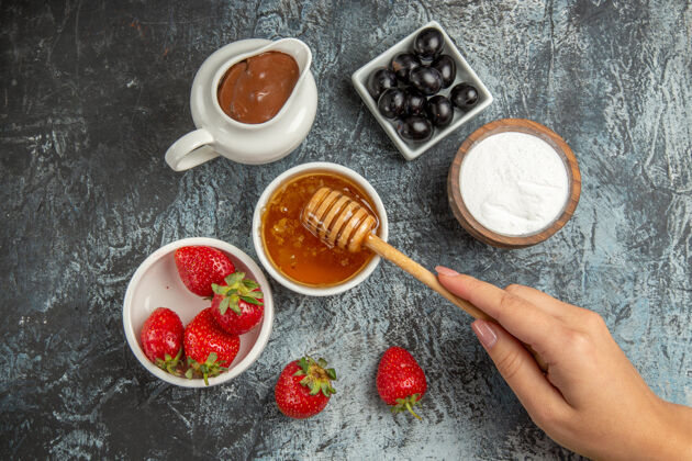 早餐顶视图新鲜草莓与蜂蜜和橄榄在黑暗的表面水果甜果冻视图容器食物