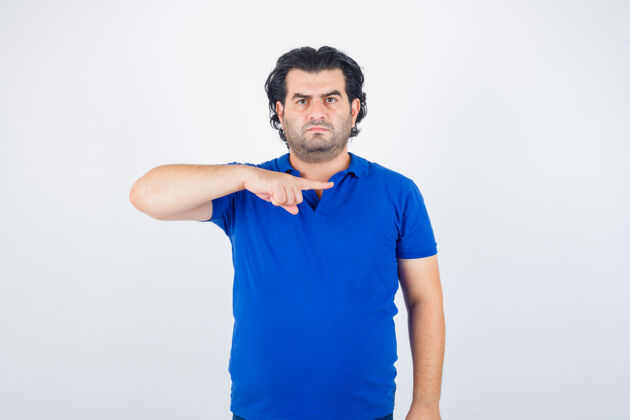 愤怒一个穿着蓝色t恤 牛仔裤 用食指指着右边 看起来很生气的成熟男人 正面视图愤怒暴躁不安