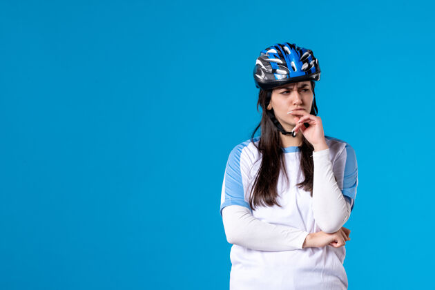 水平前视图穿着运动服的年轻女性 蓝色墙上戴着头盔视图肖像男人