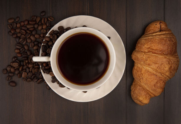 人一杯咖啡的顶视图 羊角面包和咖啡豆被隔离在木墙上咖啡风景杯子