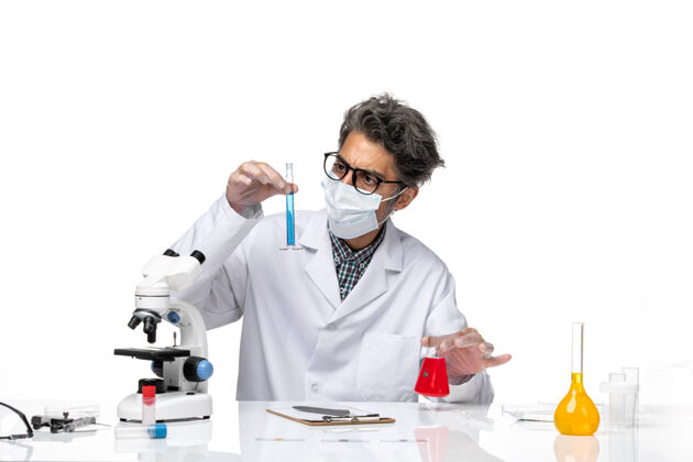实验正面图穿着特殊套装的中年科学家坐着拿着装有解决方案的烧瓶临床科学技师