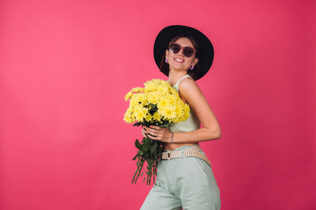 祝贺漂亮时尚的女人戴着帽子和墨镜摆造型 捧着一大束黄紫苑 春意盎然 积极向上的情感与世隔绝植物学无忧无虑节日