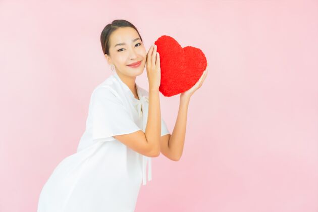 心在粉红色的墙上画一幅美丽的亚洲年轻女子的心形枕头情人节人举行