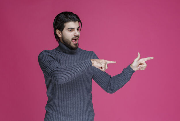 男性穿灰色毛衣的人用手指指着什么东西或介绍某人年轻表演场景