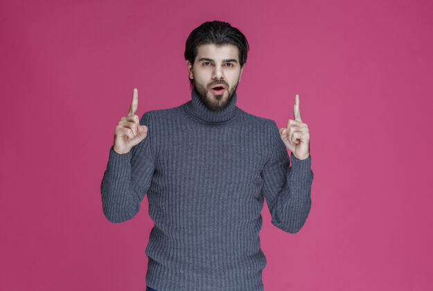 摄影穿灰色毛衣的人用手指指着什么东西或介绍某人男性促销年轻