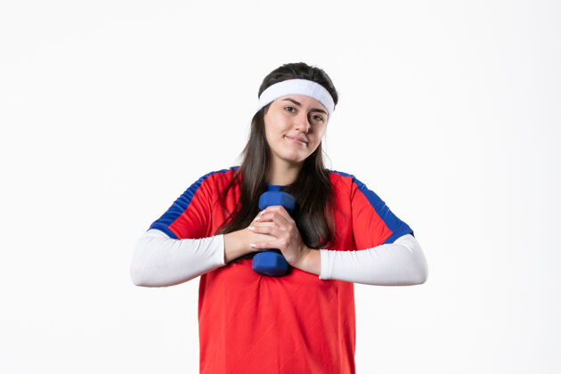 视图正面图穿着运动服的年轻女性在白墙上用哑铃锻炼年轻女性白色正面