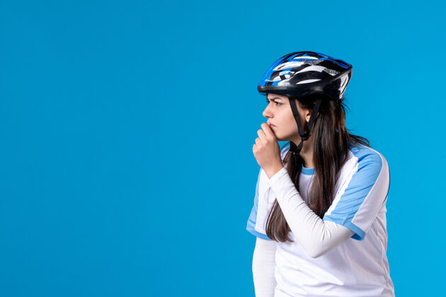 人前视图穿着运动服的年轻女性 蓝色墙上戴着头盔肖像思考蓝色