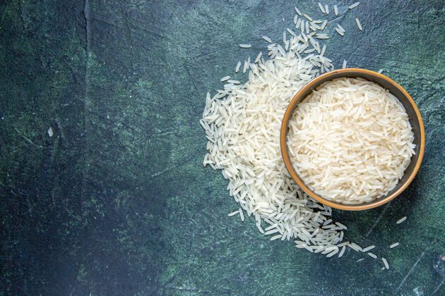 米饭在黑暗的桌子上的盘子里俯瞰生米深色灰泥质地