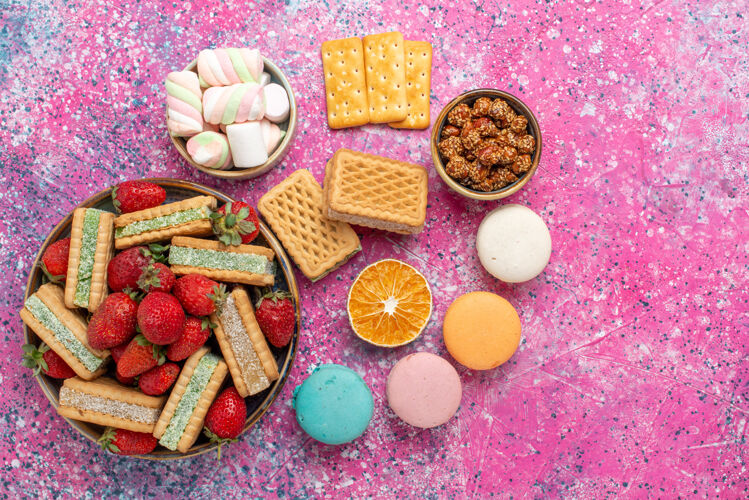 生的美味的华夫饼干俯视图 粉色表面有棉花糖 麦卡龙和新鲜的红色草莓新鲜糖果糖果