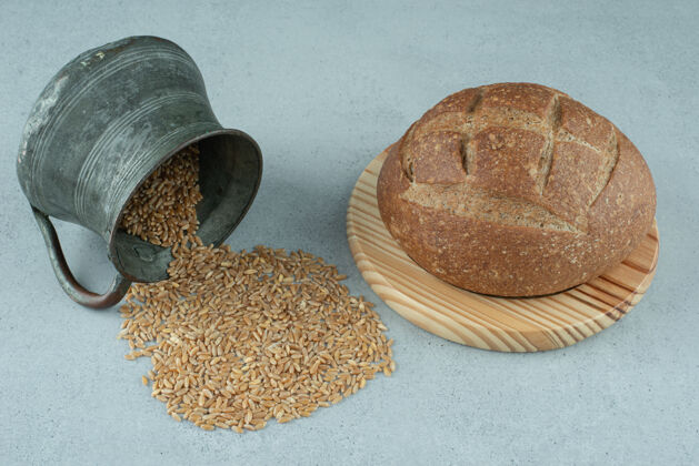 董事会黑麦面包卷放在木板上 配上一大杯大麦面包地壳黑麦