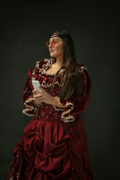 肖像穿着现代眼镜自拍穿着红色复古服装的中世纪年轻女子 深色背景好历史服饰