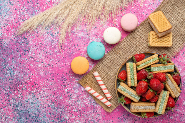 顶视图粉色表面有美味的华夫饼干和法国马卡龙的俯视图生的食物美味