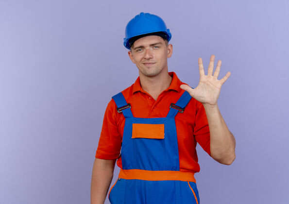 安全高兴的年轻男性建设者穿着制服和安全帽显示五对紫色头盔男请