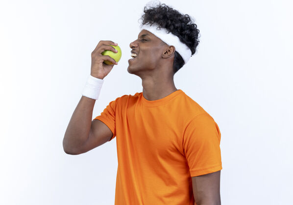 运动站在侧视图年轻的运动男子戴头带白苹果腕带