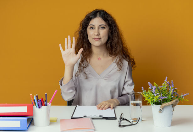 漂亮年轻漂亮的女上班族坐在办公桌旁 拿着办公工具 用橙色表示问候坐着你好请