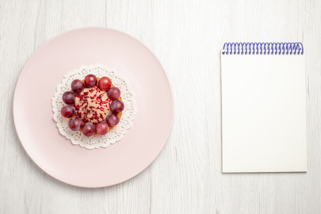 蛋糕顶视图小蛋糕与葡萄在盘子里放在白色的桌子上 水果甜点蛋糕盘子笔记顶部