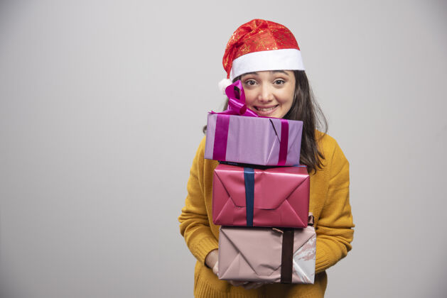 微笑微笑的戴着圣诞帽的女人手里拿着礼品盒肖像冬天模型