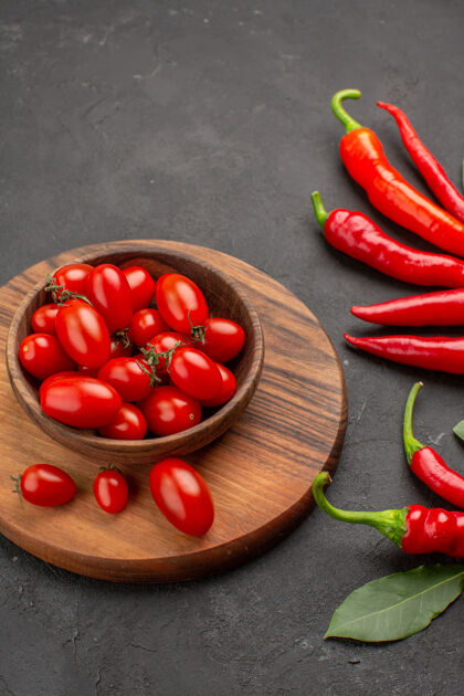 辣椒在黑色桌子上的砧板上近距离观看红辣椒 荷叶和一碗樱桃西红柿 有足够的空间番茄桌子健康