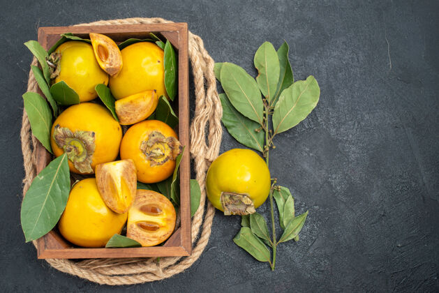 深色顶视图新鲜甜甜的柿子在盒子里放在深色的桌子上 水果味道成熟柑橘食物成熟