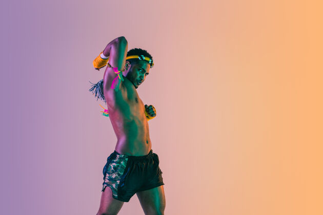 曼谷泰拳年轻人在霓虹灯下的梯度背景上练习泰拳拳击力量斗士