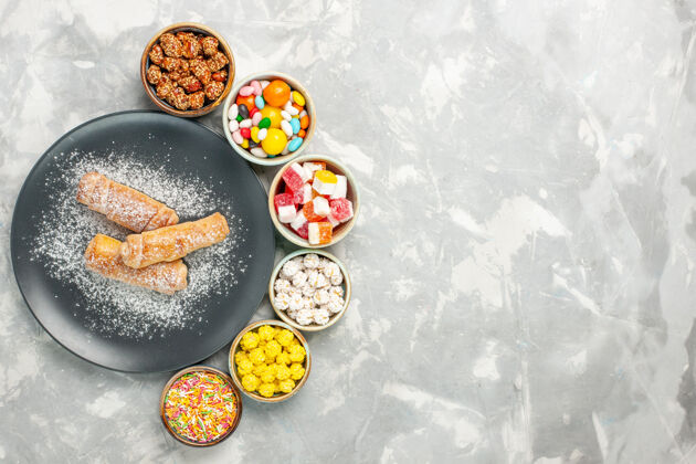 餐俯视美味的甜百吉饼糖粉与不同的糖果在白色表面传统的粉末美味