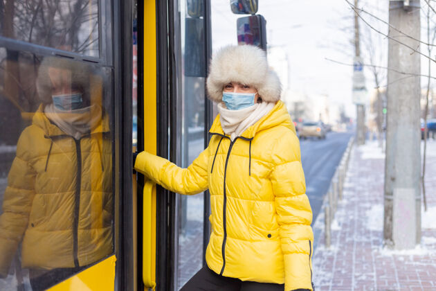 公共汽车一个微笑的年轻女人在冬天走进公共汽车等待城镇交通