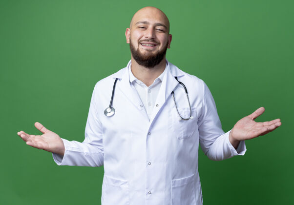 年轻面带微笑的年轻男医生穿着医用长袍和听诊器 将双手隔离在绿色上听诊器穿微笑