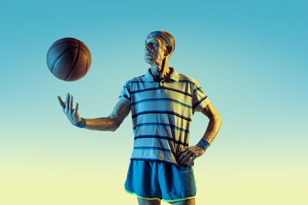 健康穿运动服的老人在渐变背景下打篮球 霓虹灯姿势欢呼球拍