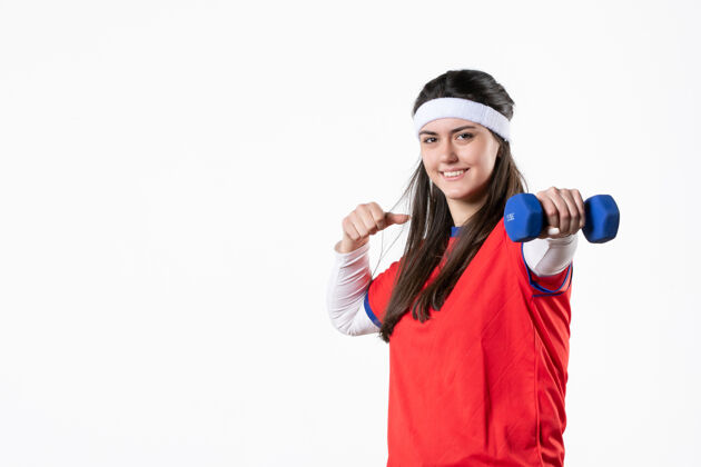 比赛正面图微笑的年轻女性穿着运动服 手拿蓝色哑铃白色锻炼青少年
