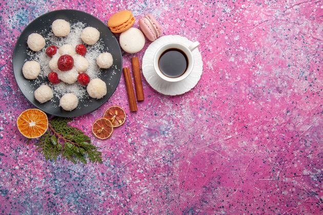 糖果美味的椰子糖和一杯茶在粉红色的表面俯瞰含糖美味茶