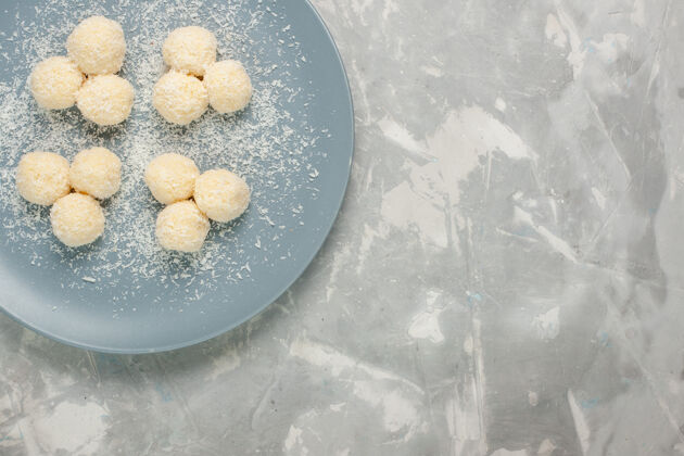 生的白色表面上蓝色盘子内美味椰子糖的俯视图美味水饼干