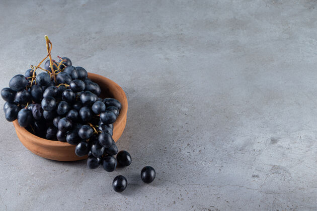 多汁石头桌上放着一碗新鲜的黑葡萄食物收获黑色