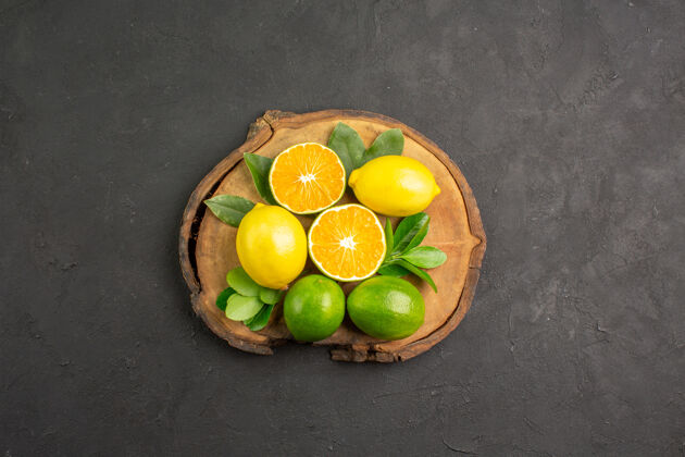 顶部在一张深色的桌子上俯瞰新鲜的酸柠檬 柑橘 酸橙和水果史密斯奶奶柠檬健康