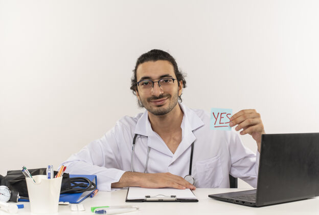 工具年轻的男医生戴着医用眼镜 穿着带听诊器的医用长袍眼镜坐着年轻