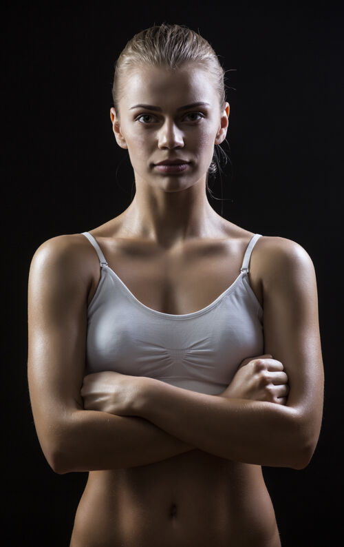 胃运动型肚皮女人孤立地站在黑暗的背景上年轻瘦健康