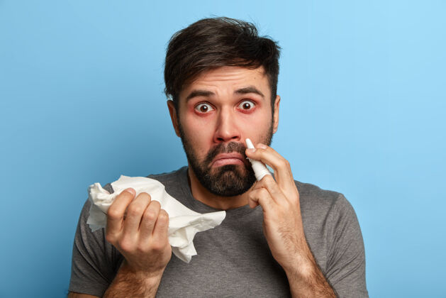 吹没刮胡子的惊讶男子患有季节性流感病毒 感冒了 用滴鼻液治鼻塞 拿着手帕 清理鼻塞 得了过敏性鼻炎 感觉很不好症状病毒吸入器