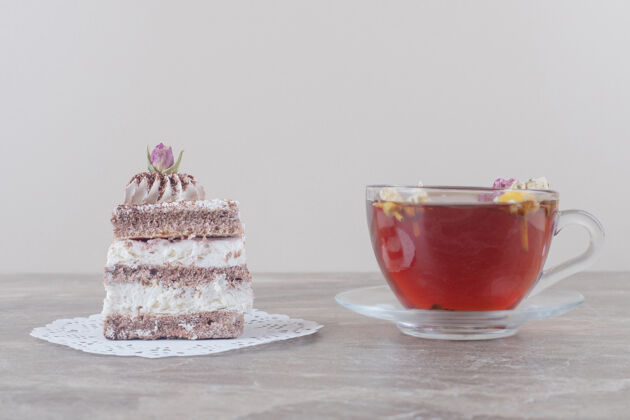 美味一杯茶和一块蛋糕放在大理石上的小垫子上切片美味茶